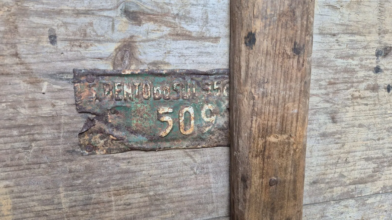 Placa metálica enferrujada pregada na madeira da carroça, com a inscrição S. Bento do Sul e o número 509